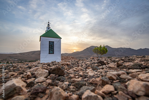 small cute white wooden chapel in a barren volcanic landscape. Sunset, landscape shot of the Ermita Protestante de Violante church, on the island of Fuerteventura, Canary Islands, Spain photo