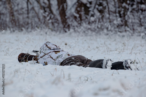 Nature photographer lying in the snow taking photos