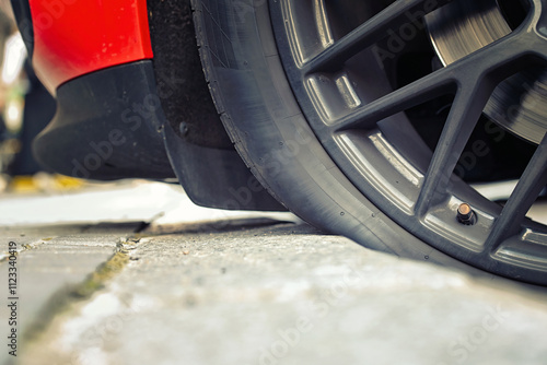 Obraz na płótnie Car tire touching the curb in parking lot closeup. Automobile wheel parked nearcurb with the tire brushing against it, parking precision and the hazards of rim or sidewall damage. Selective focus w salonie