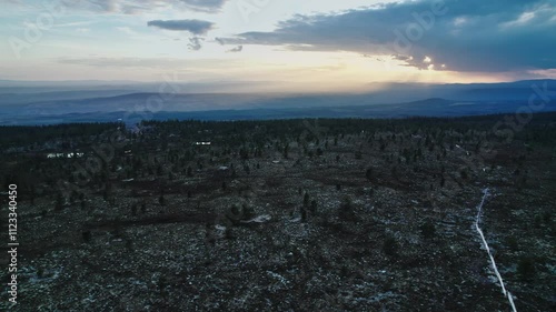 Experience a stunning summer evening as a drone glides over a mountain ridge in Idre Dalarna, Sweden, showcasing a fiery sunset sky and beautiful sun rays illuminating the tundra
