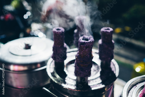 Cooking Puto bumbong, a popular Filipino delicacy of steamed purple rice cakes in sticky logs sold traditionally during Christmas season in night market. Selective focus.