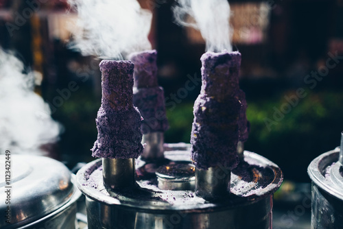 Cooking Puto bumbong, a popular Filipino delicacy of steamed purple rice cakes in sticky logs sold traditionally during Christmas season in night market. Selective focus.