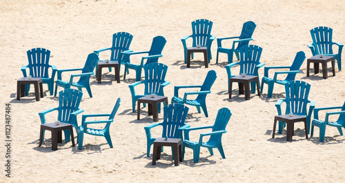 Outdoor seating area on the beach with black and blue plastic chairs and tables.