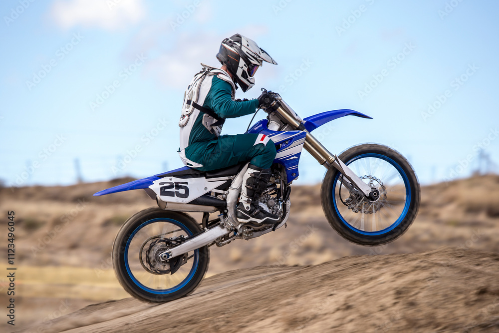 Obraz premium profile view of motocross racer going off jump