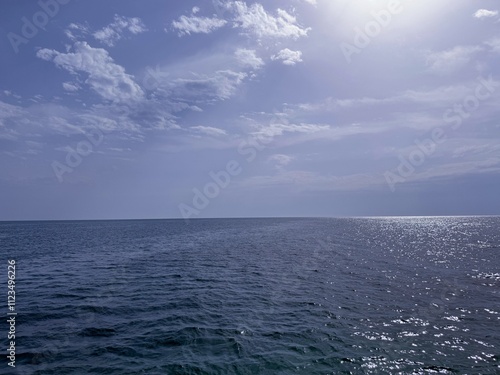 Ocean expanse blue shimmering water and cloudy sky.  photo