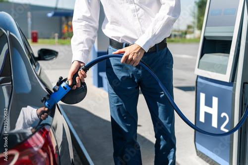 Man holds a hydrogen fueling nozzle on a hydrogen filling station. Refueling car with hydrogen fuel.	 photo