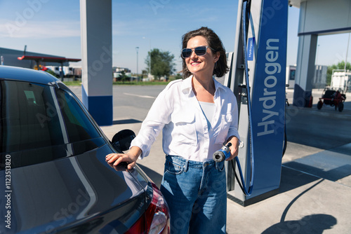 Woman holds a hydrogen fueling nozzle on a hydrogen filling station. Refueling car with hydrogen fuel. photo