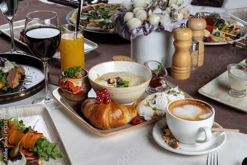 Breakfast. Fruits, croissants, porridge, poached eggs. On rustic dark wooden table.