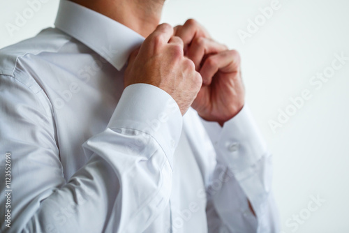 Close-up of male hands buttoning a white shirt. Men's classic white shirt.