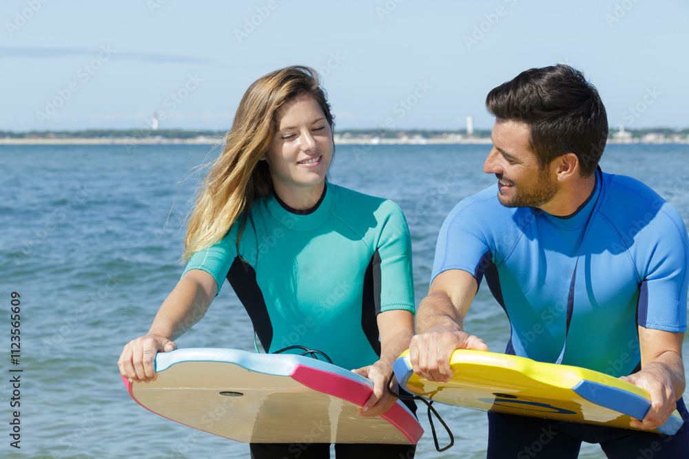 Obraz premium couple by the sea practicing position for bodyboarding