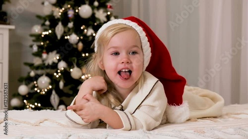 Cute Little girl child in beautiful pajamas near the Christmas tree at home, the concept of New year and Christmas.