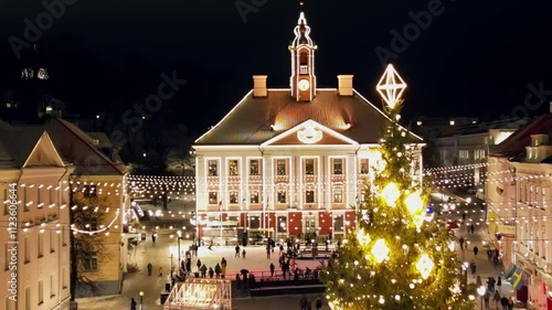 Christmas market in the center of Tartu Estonia, In the middle of the main square, there is a big Christmas tree decorated with bright yellow lights and an ice skating rink, people enjoy hanging out