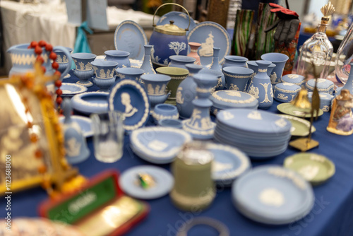 London, UK - December 1, 2024, a flea vintage market in Covent Garden. Blue royal Wedgwood porcelain, an antique English tea set, figurines, and a crocheted lace tablecloth for sale on display. photo