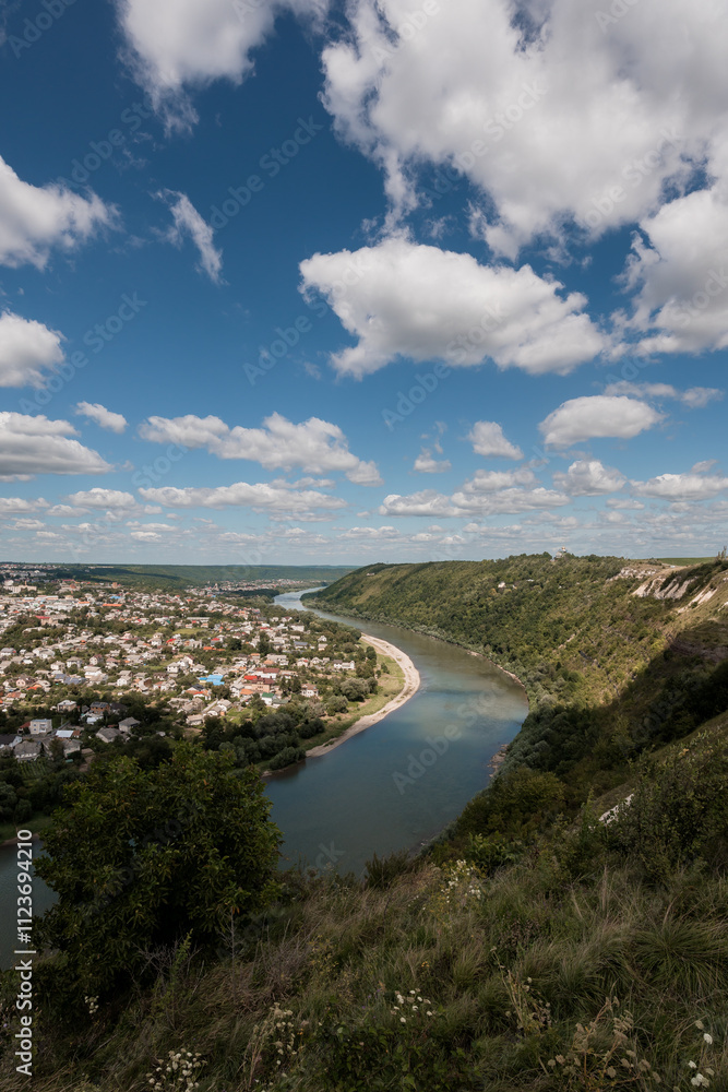 Obraz premium Serene View of a Meandering River and Lush Greenery Under a Cloudy Sky