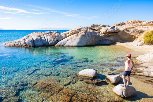 Woman tourist standing on rock at beautiful sandy beach of Mikri Vigla, Naxos island, Cyclades, Greece photo