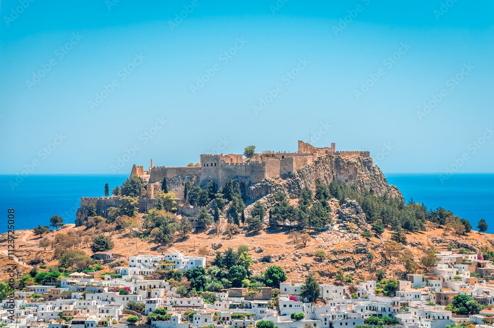 Obraz premium The village of Lindos with whitewashed houses and the iconic Acropolis on top of the hill. In Rhodos Island, Dodecanese, Greece.