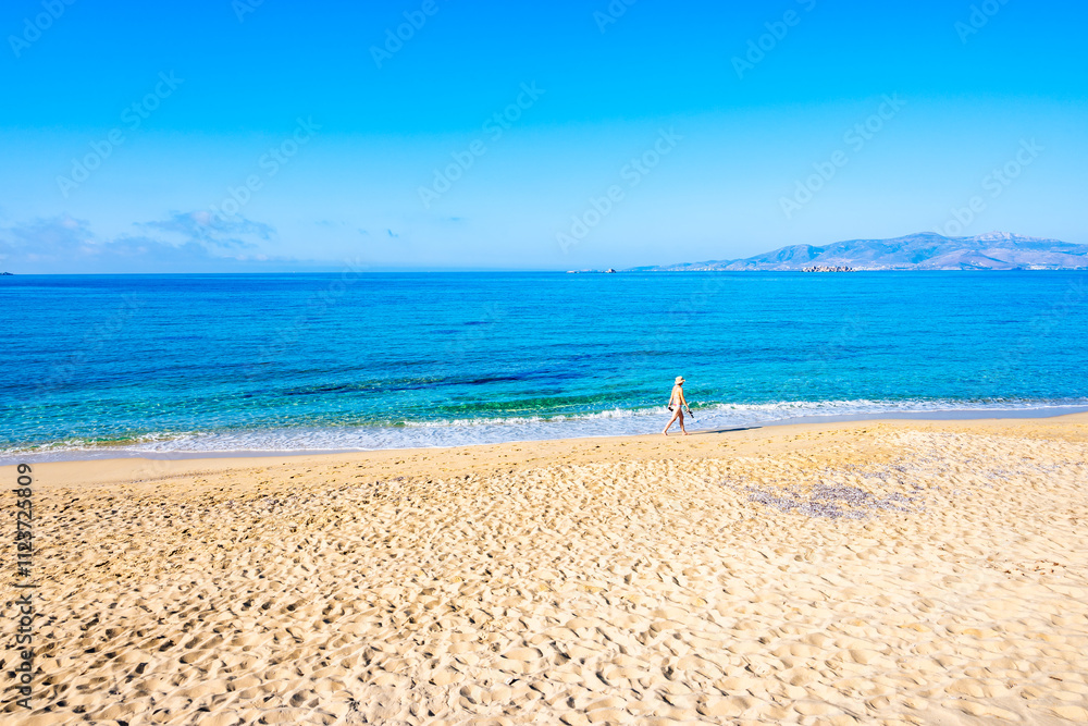 Young woman walking along sea on sandy Plaka beach, Naxos island, Cyclades, Greece