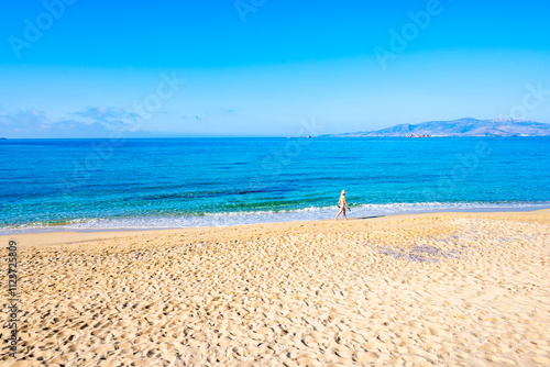 Obraz na płótnie Young woman walking along sea on sandy Plaka beach, Naxos island, Cyclades, Greece w salonie