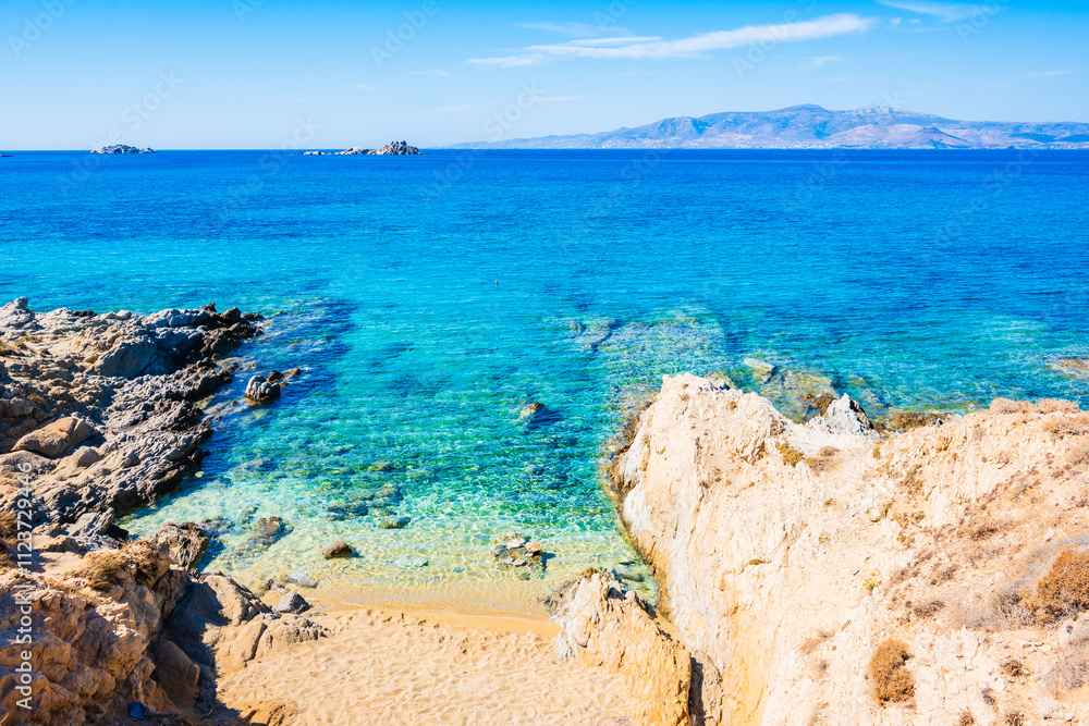 Rocks and stones on idyllic sandy beach of Orkos bay and calm crystal clear azure sea water, Naxos island, Cyclades, Greece