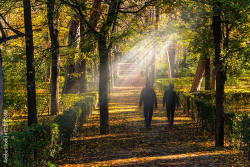 Couple walking in the sunlit path of retiro park in autumn