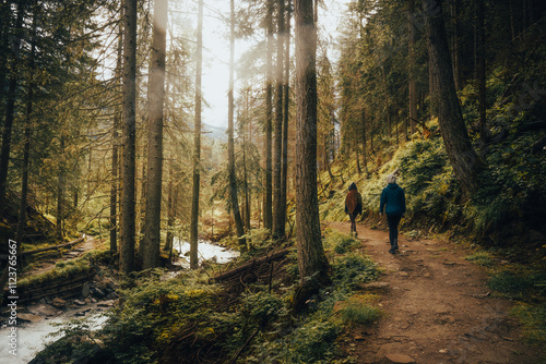Two people are leisurely walking down a serene path in the woods