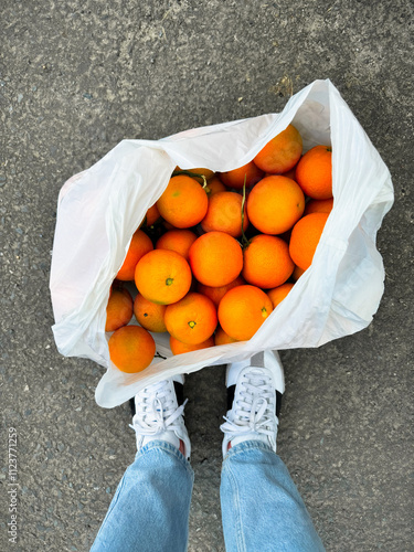 A bag of oranges at the girl's feet