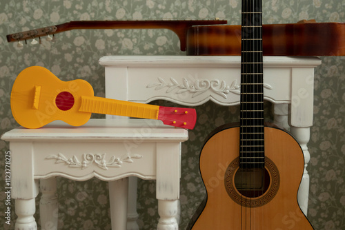 Wallpaper Mural Three different guitars in a composition: a yellow toy guitar and two acoustic guitars, paired with decorative white tables with carved details against a green background. Music, art, and hobbies Torontodigital.ca