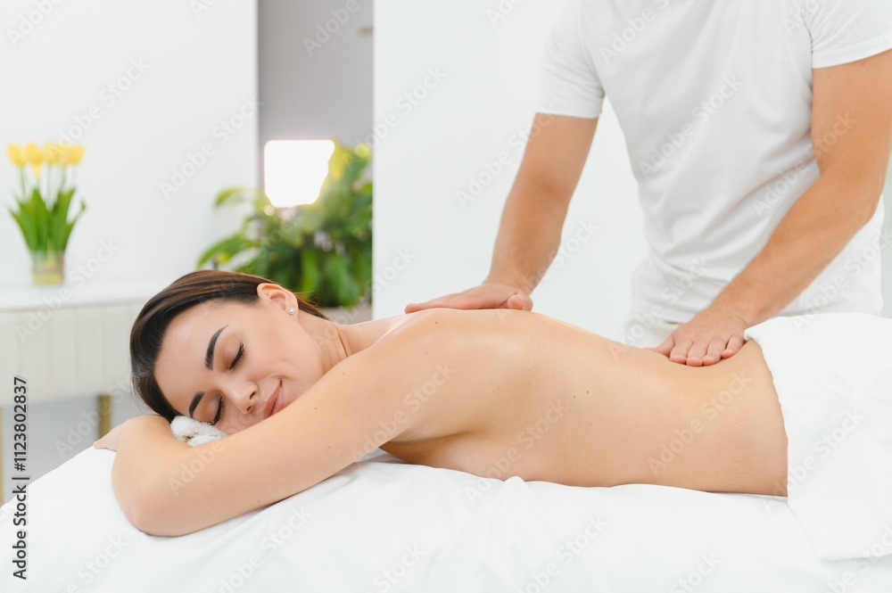 Obraz premium Osteopath massaging back of woman lying on front in health spa