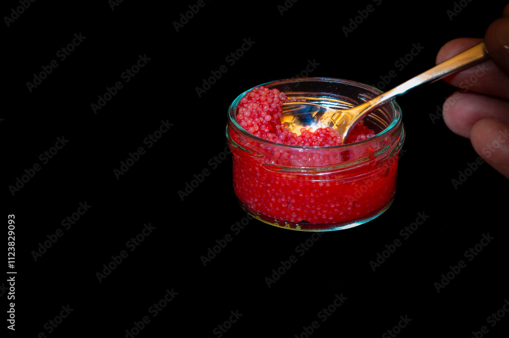 red lumpfish roe in a glass jar against black background