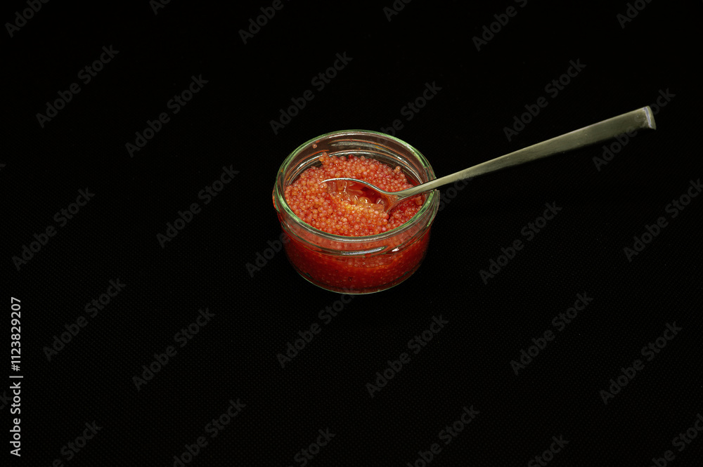 red lumpfish roe in a glass jar isolated on black