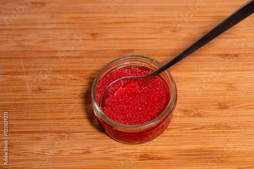 red lumpfish roe in a glass jar on a cutting board