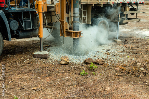 In an outdoor setting, this powerful auger drilling rig is captured in full operation, exemplifying technology and efficiency in soil drilling processes. The robust machine, with its yellow metal stru