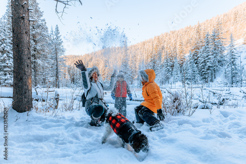 Mother and children having fun in the snow with their dog on a beautiful wintry day