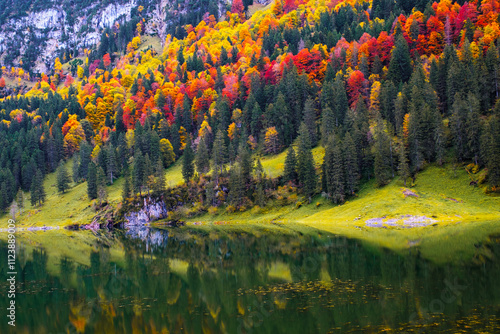 In the heart of Appenzell, Falensee showcases stunning autumn foliage, with vibrant reds and yellows mirrored in crystal-clear waters, surrounded by majestic peaks and lush greenery in Switzerland photo