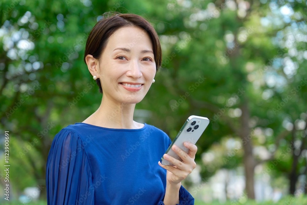 公園でスマホを持つ女性 カメラ目線 公園でスマホを持つ女性 カメラ目線