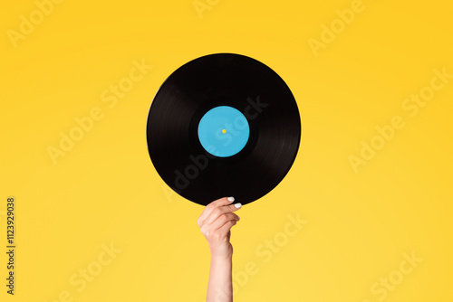 Girl hand showing retro vinyl gramophone record on pink background, close up photo