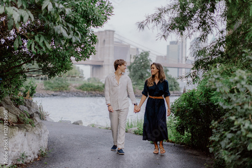 A romantic scene of a couple strolling hand in hand along a waterfront, surrounded by lush greenery and tranquility. Brooklyn bridge in New York.