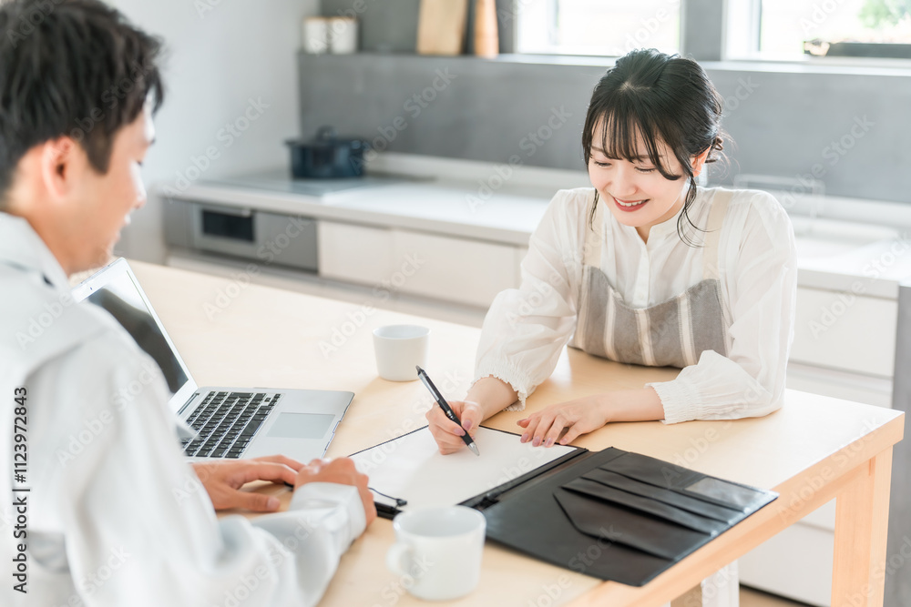 Fototapeta premium 契約書・同意書にサインを求める作業着姿の営業マンの男性とサインをする主婦・女性 
