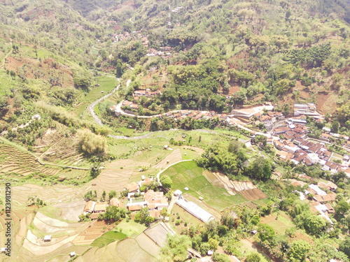 Aerial Picture of Cicalengka Green and Lush Valley in summer, Bandung, Indonesia. The valley shows winding road, small river, and village surrounded by Hill and Mountain. photo