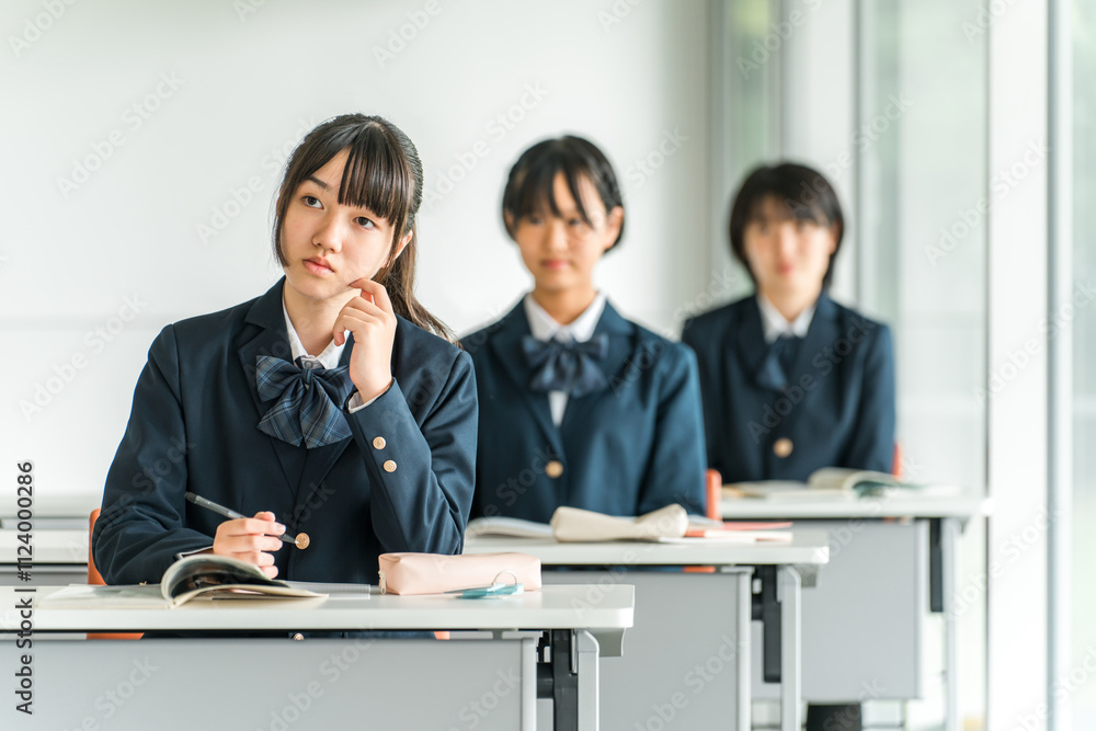 Obraz premium 学校の教室で真剣に授業を聞く制服姿の小学生・中学生・高校生・女子高生(友達)