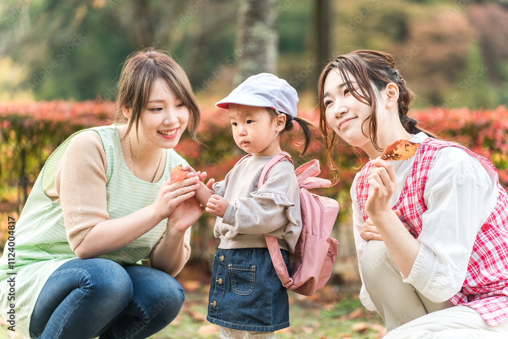 Obraz premium 秋の公園を散歩・遠足する保育士の女性と園児（保育園・幼稚園保母・子供・幼児） 