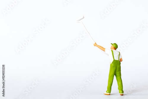 A miniature figure of a painter using a long roller brush to paint on a white background