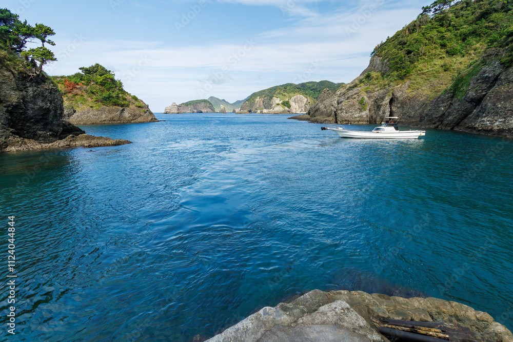 Fototapeta premium ヒリゾ浜渡船の漁船に乗って、海に出るスキンダイバー、シュノーケラーたち。 ヒリゾ浜の青い海と無人島の大根島、数多くの岩礁が見えている。 静岡県伊豆半島賀茂郡南伊豆町中木ヒリゾ浜2024年 