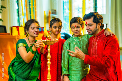 Closeup of Indian family in traditional attire lighting diya or samai on a festive day with joy photo