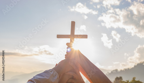 Friendship hands praying and holding Christian cross for worshipping God on mountain at sunrise background. Christian, Christianity, Religion copy space background. Easter Sunday concept: