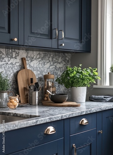 Modern, navy blue kitchen cabinets with granite countertop, featuring a variety of kitchen utensils, a cutting board, and plants. photo