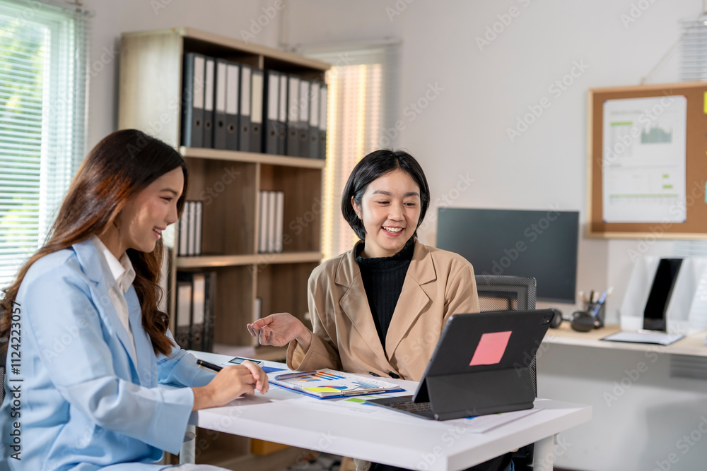 Two businesswomen sharing ideas and working together on project using digital tablet at the office Two businesswomen sharing ideas and working together on project using digital tablet at the office