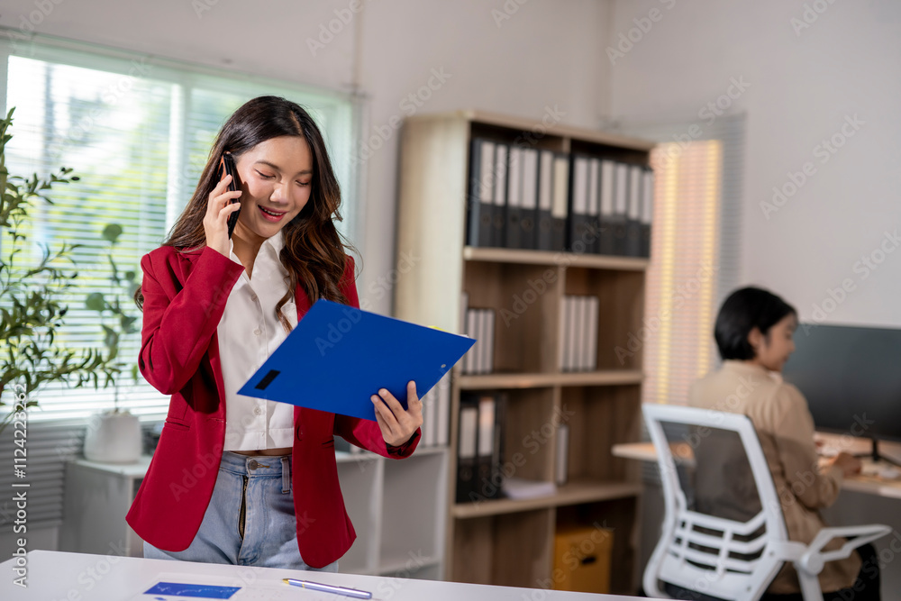Businesswoman smiling and talking on the phone while reading a document in office Businesswoman smiling and talking on the phone while reading a document in office