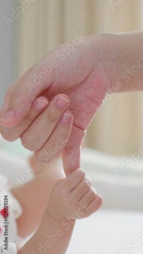 A baby sleeps peacefully, their tiny hand wrapped around their mother’s finger, a tender connection radiating love, warmth, and unspoken trust.