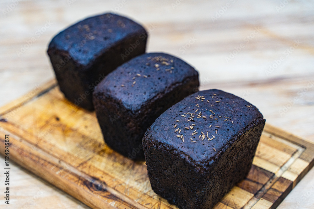 Three loaves of caraway rye bread on a wooden cutting board in the bakery. Three loaves of caraway rye bread on a wooden cutting board in the bakery.